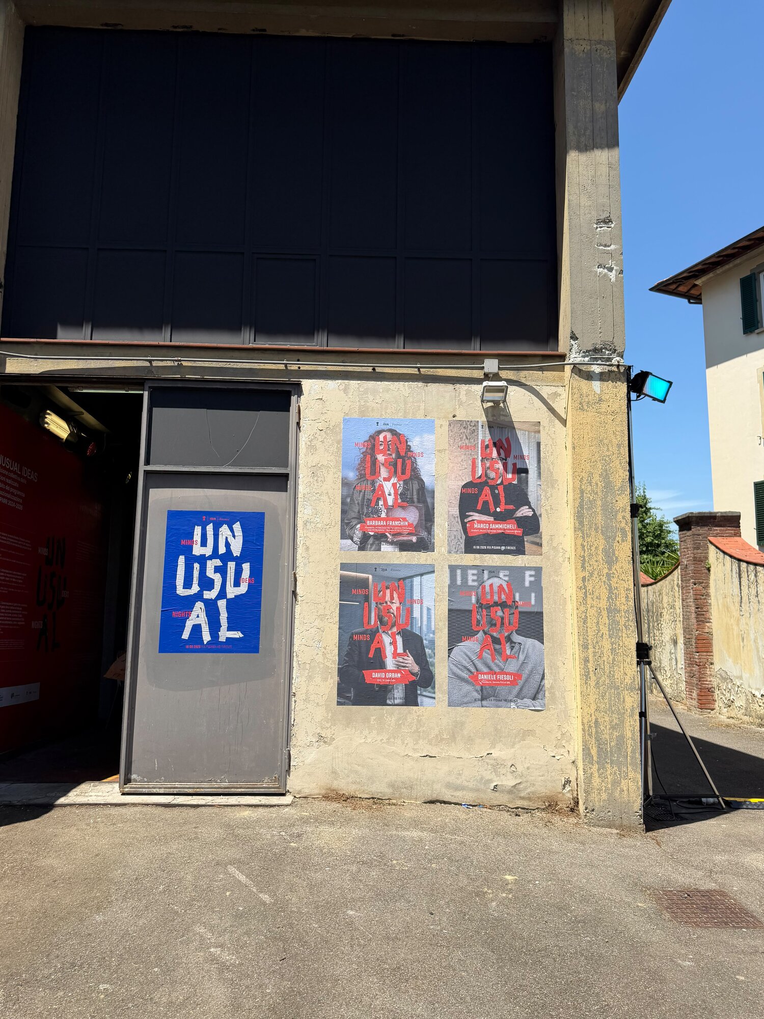 Az ISIA Firenze UNUSUAL eseményének plakátjai egy falon a via Pisanán, David Orbannal az előadók között
